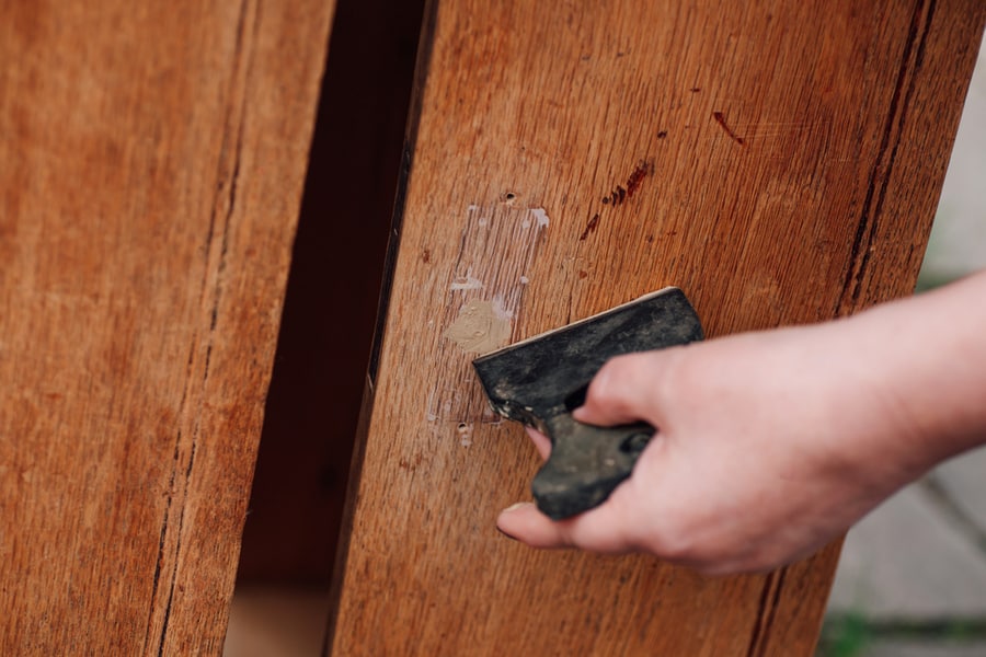 Close-Up A Woman's Hand Holds A Spatula And Puts Putty On A Hole