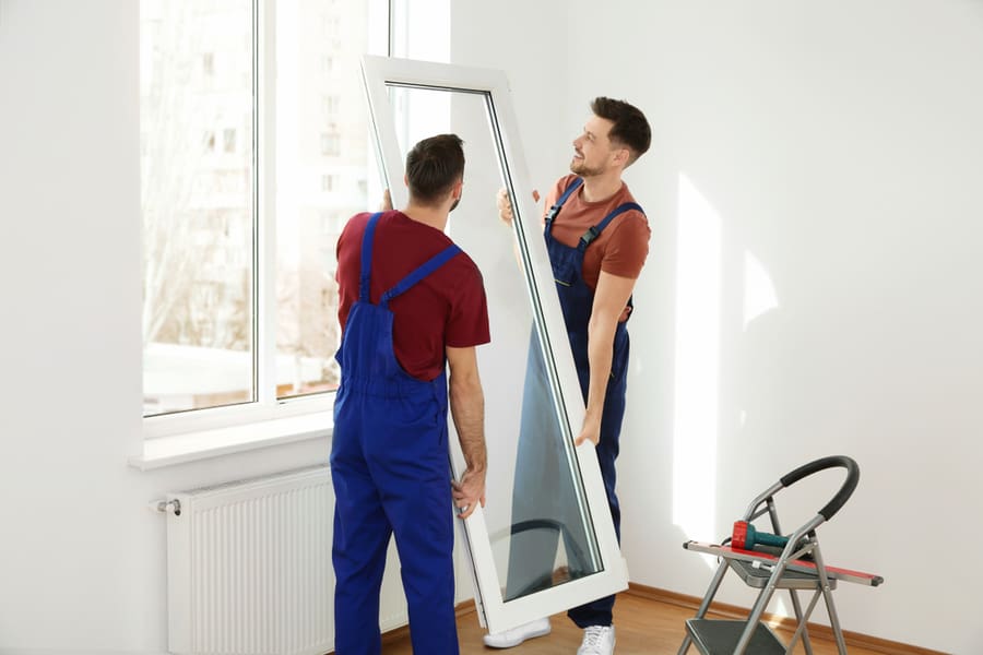 Construction Workers Installing Window In House