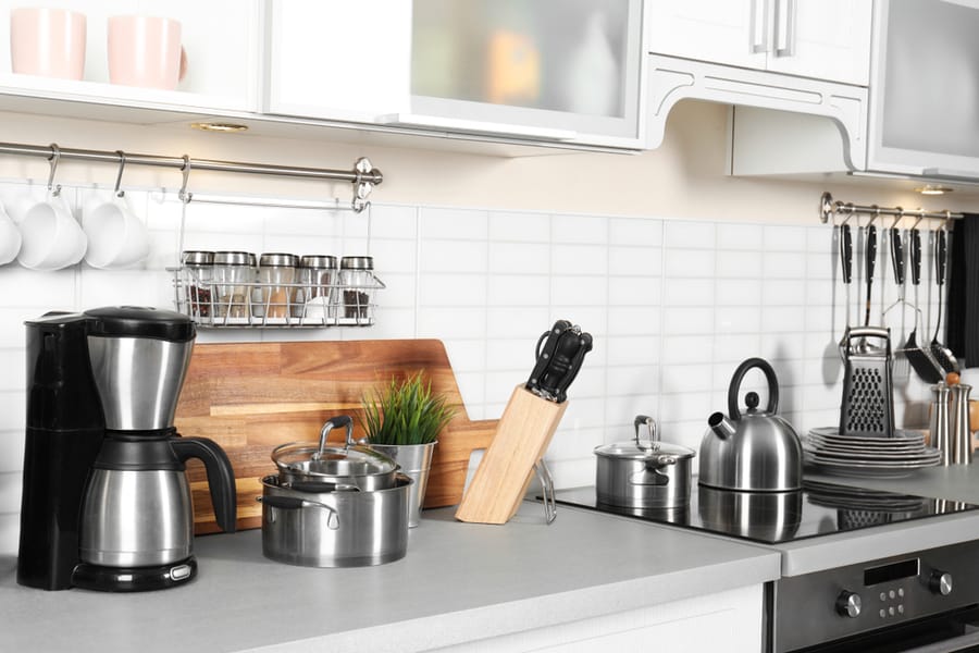 Different Appliances, Clean Dishes And Utensils On Kitchen Counter