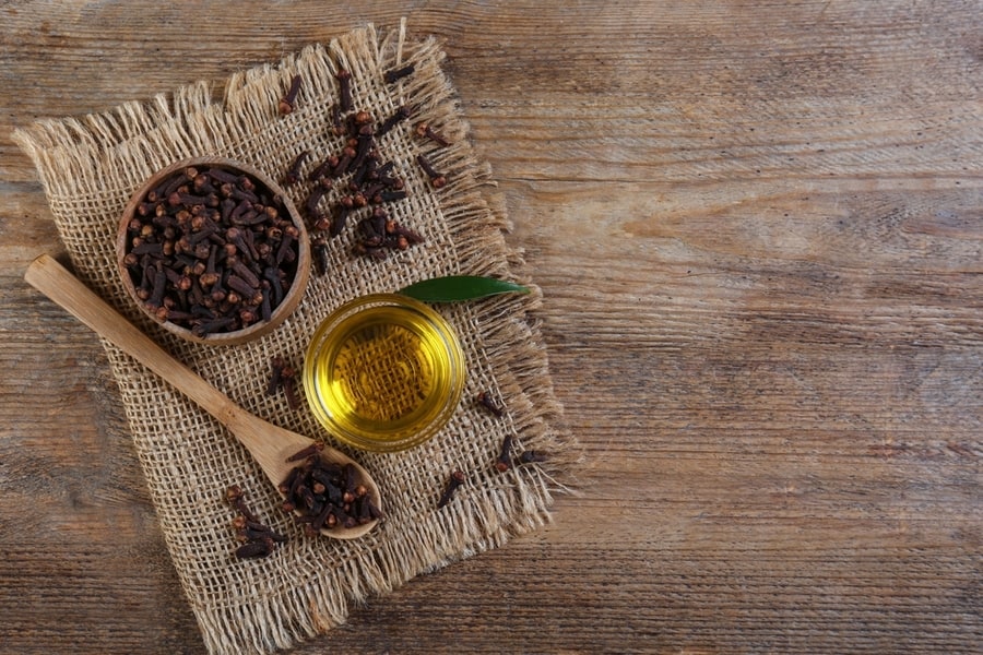 Essential Oil And Dried Cloves On Wooden Table, Flat Lay