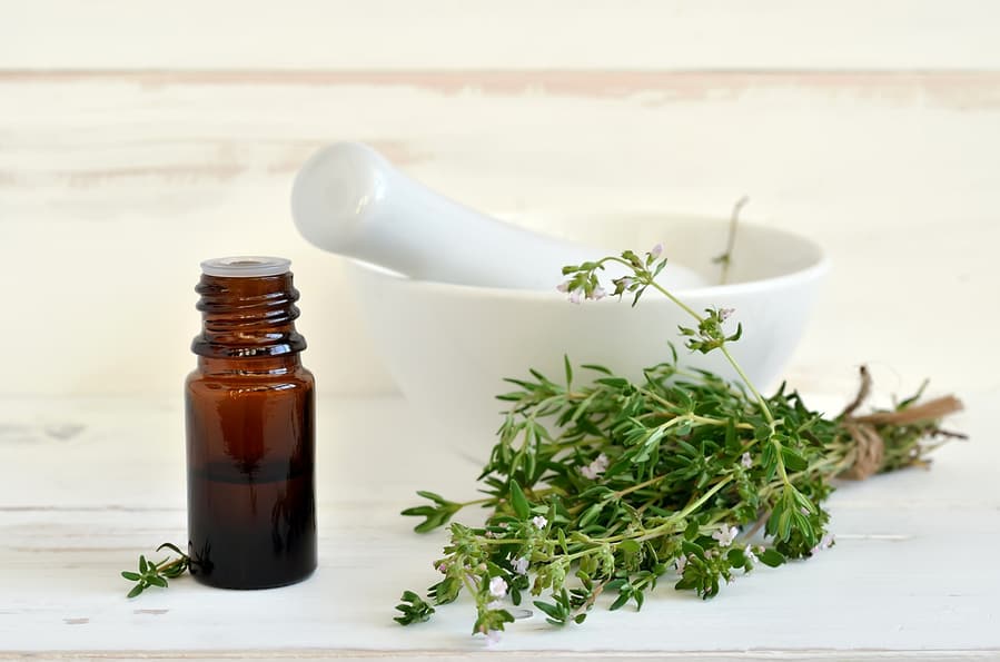 Essential Thyme Oil In Dark Glass Bottle With Thyme Twigs