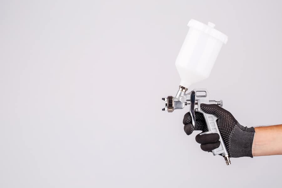 Hand And Painting Spray Gun At Work On White Background