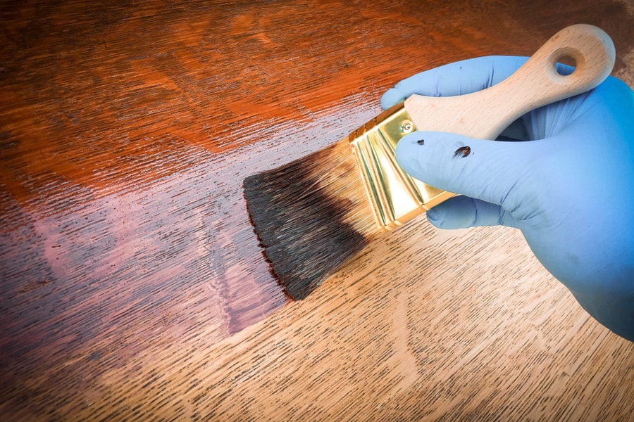 Hand Holding Brush Applying Brown Mahogany Stain