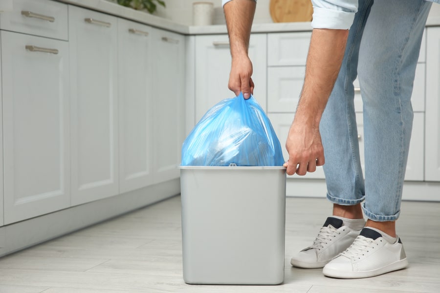 Man Taking Garbage Bag Out Of Bin At Home