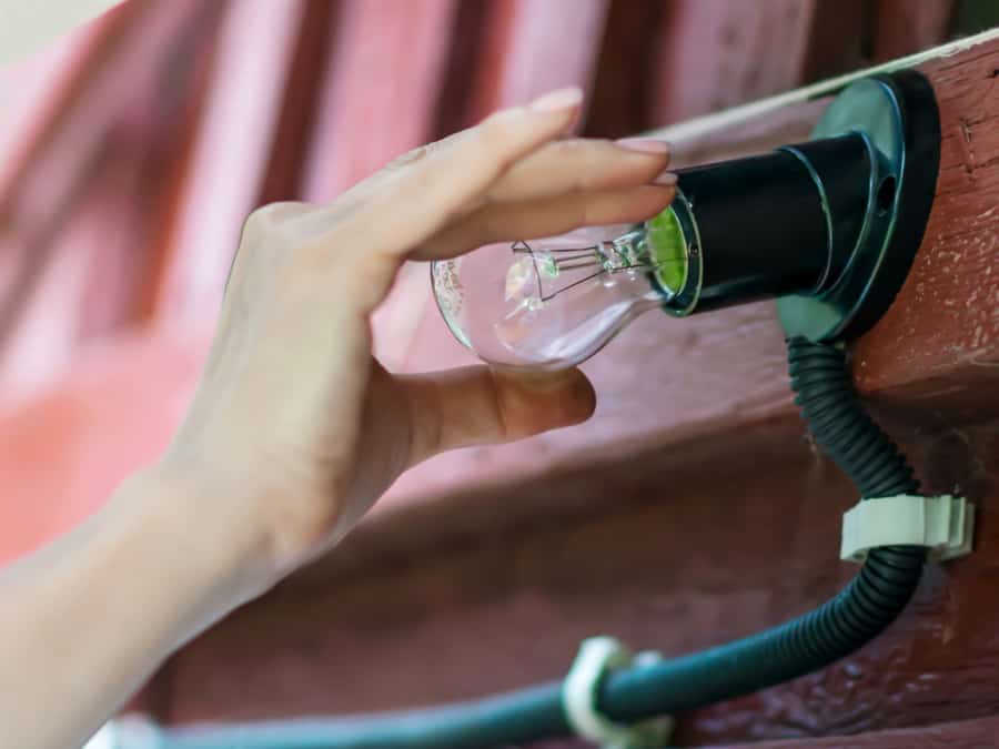 Person Changing Light Bulb On Wooden Roof