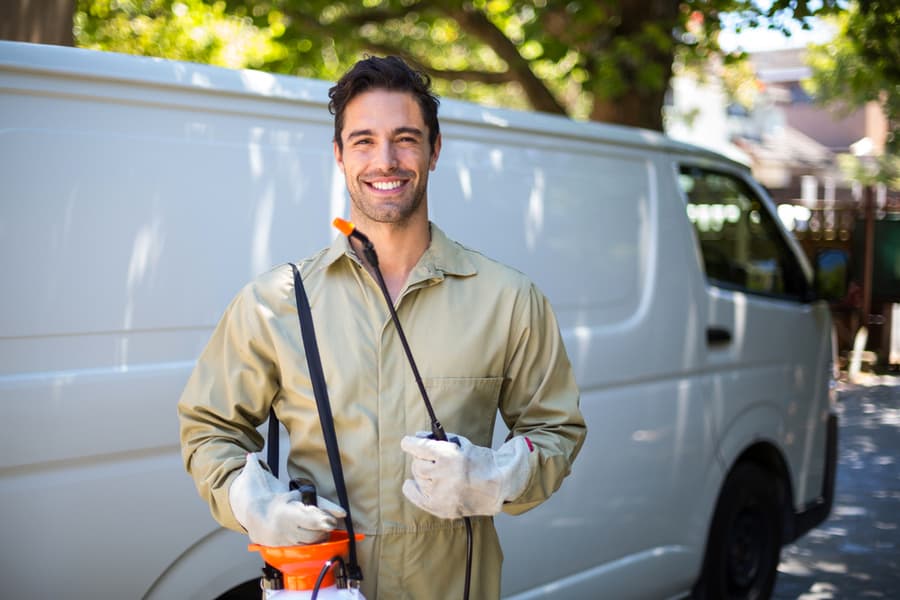 Portrait Of Smiling Worker With Pesticide Sprayer While Standing By Van