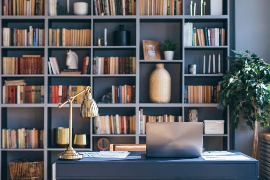 Table With Laptop In Home Office Interior, Books In The Shelfs On Background