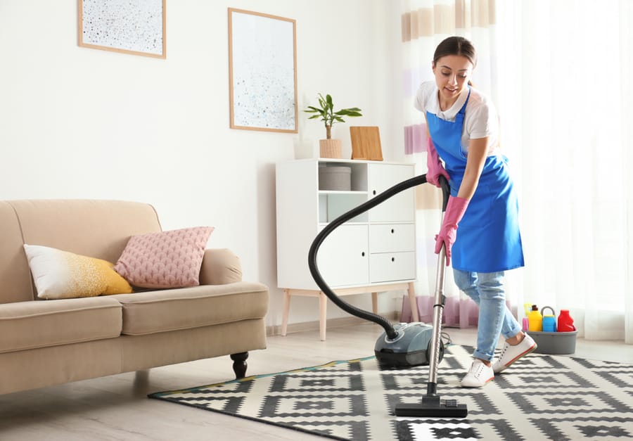 Woman Hoovering Carpet In Living Room