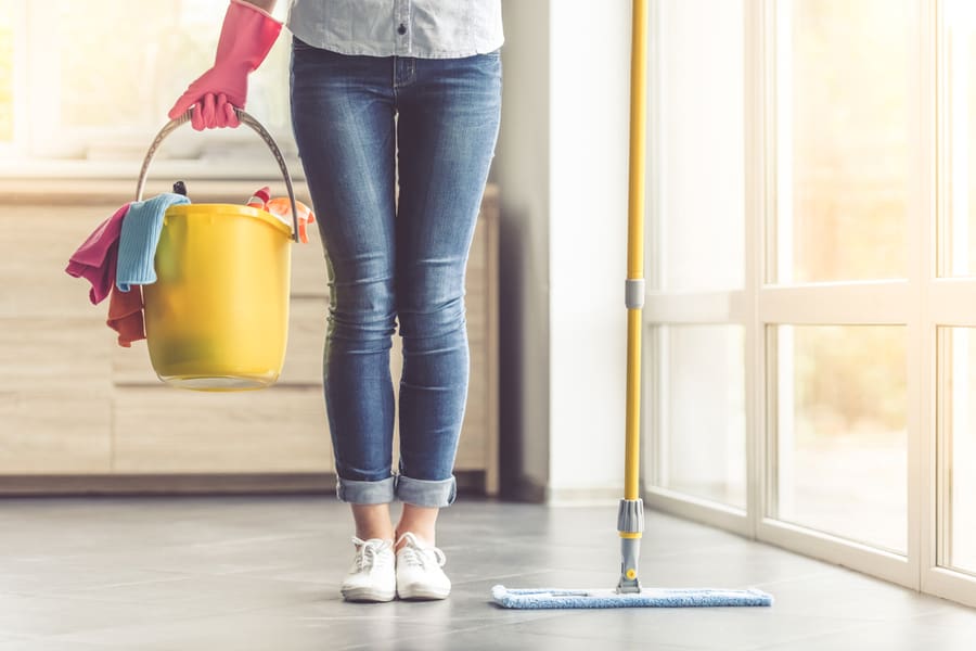 Woman In Protective Gloves Holding A Flat Wet-Mop And Bucket With Detergents And Rags While Cleaning Her House