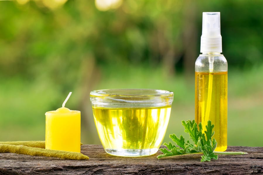 A Cup Of Citronella Essential Oil With A Citronella Candle And Spray Bottle