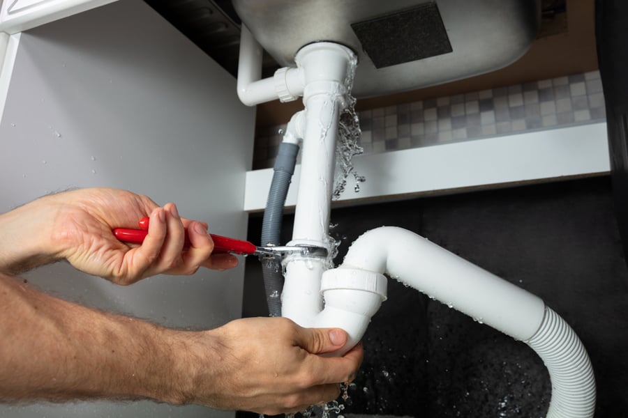 A Man Fixing A Broken Sink Pipe