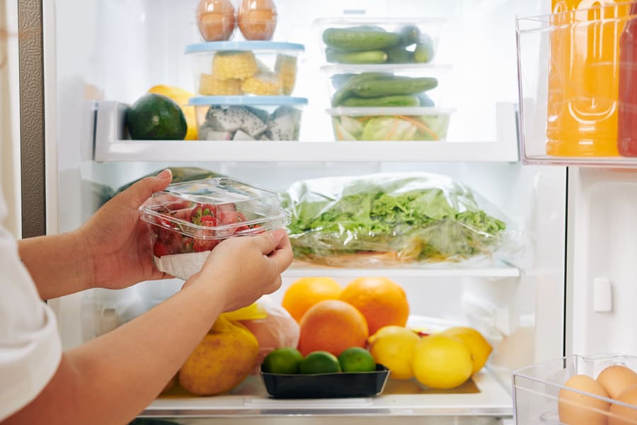 A Woman Organizing Food In The Fridge