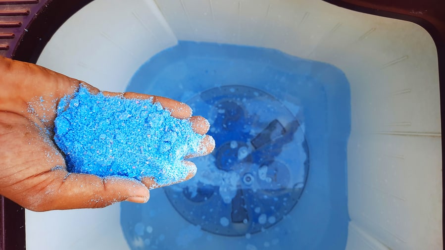 Detergent Powder In Hands And Adding It In Water