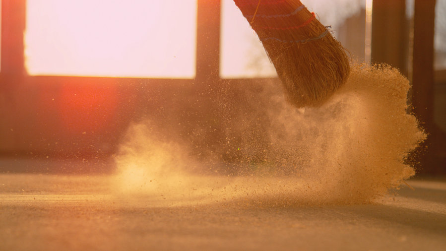 Dust Gets Swept Up Into Air As An Unrecognizable Person Cleans The Floor