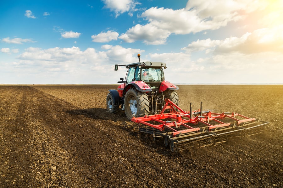 Farmer In Tractor Preparing Land