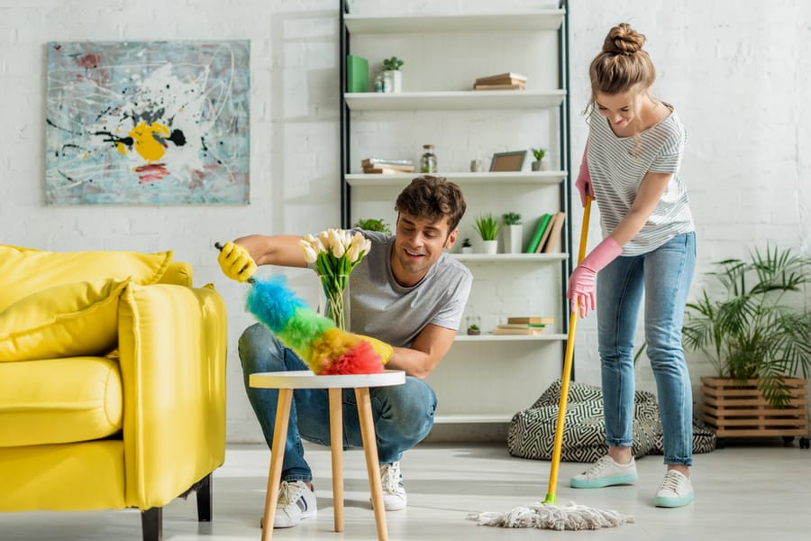 Happy Man And Woman Doing Spring Cleaning In Apartment