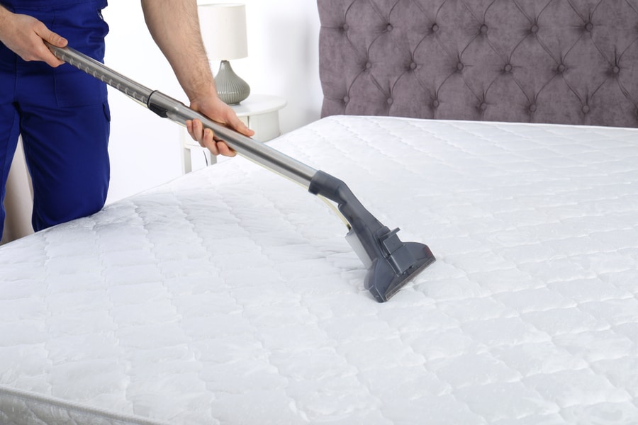 Man Disinfecting Mattress With Vacuum Cleaner