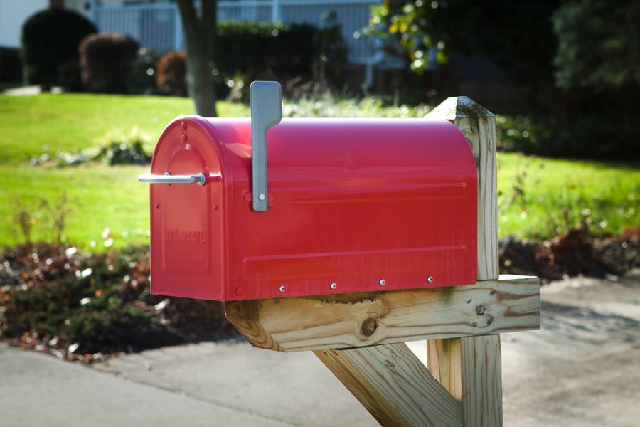 Red Rural Mailbox On A Brown Wooden Post With Silver Flag Raised Close Up