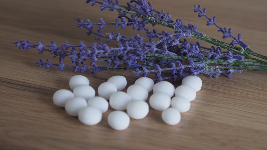 White Naphthalene Balls Or Mothballs On Wooden Table And Lavender In The Background.