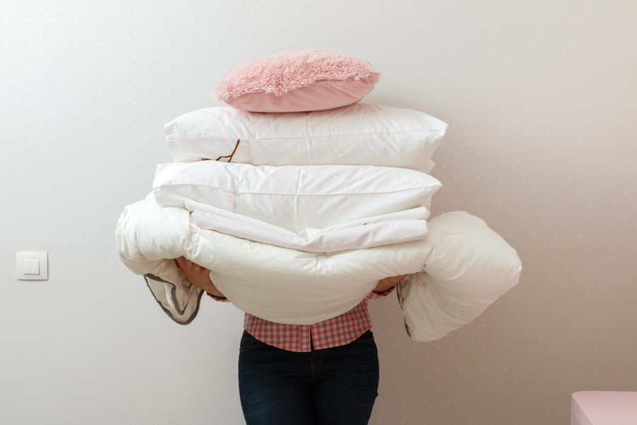 Woman Holding A Pile Of Bedding For Washing