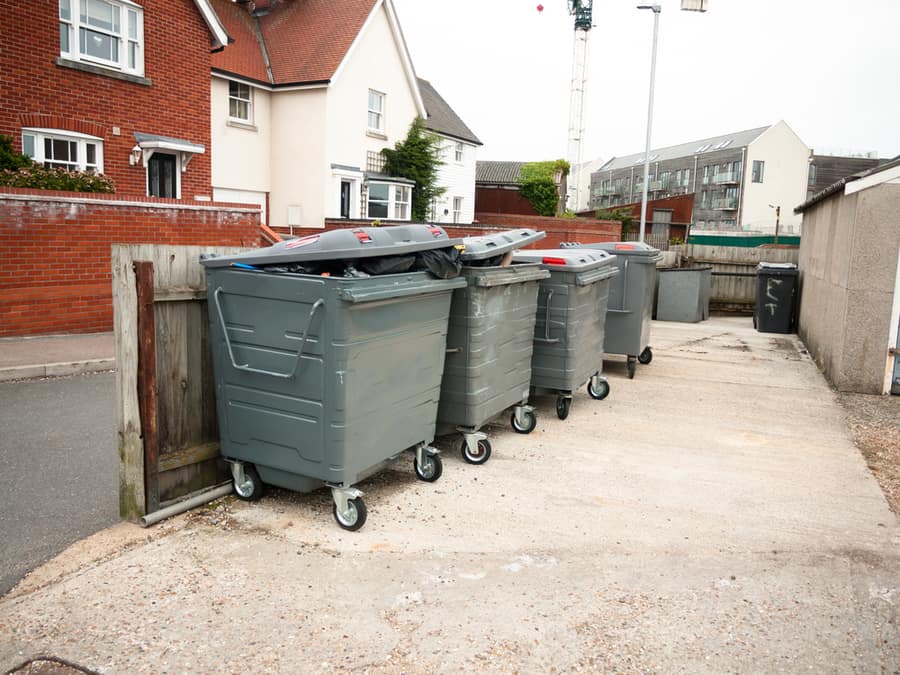 A Row Of Black Waste Bins Outside Full