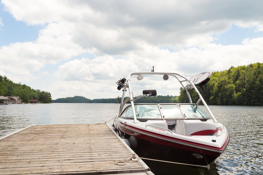 A Wakeboard Boat At A Wooden Dock In The Muskokas On A Sunny Day.