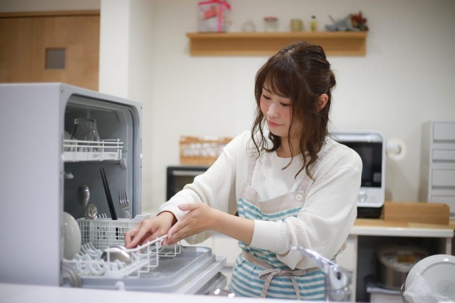 A Woman Lining Up Dishes In The Dishwasher