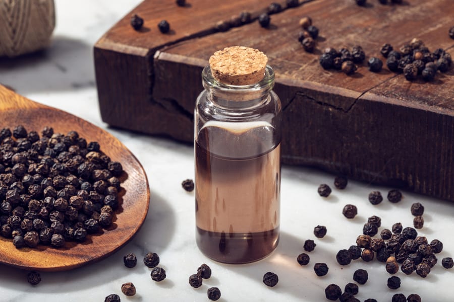 Black Pepper Essential Oil On Marble Table.