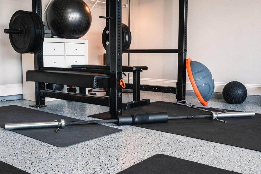 Indoor Garage Gym Setup With Home Exercise And Fitness Equipment. Lifting Rack, Bench And Bar Ready For Use. Home Gym With Natural Light.