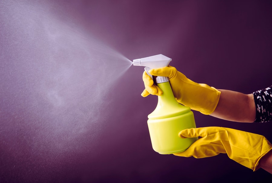 Woman Wearing Yellow Rubber Gloves Using Green Spray Bottle And Spraying