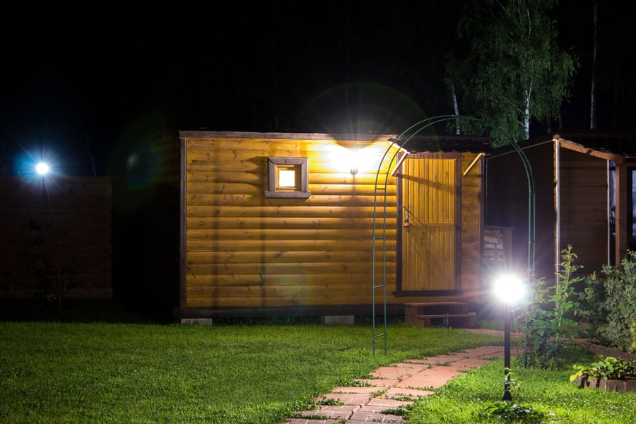 Wooden Shed On Grass Lit By Lanterns At Night