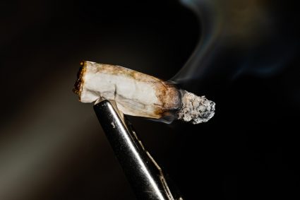 A Hand Rolled Joint Being Smoked On A Roach Clip In A Recreational Use Setting