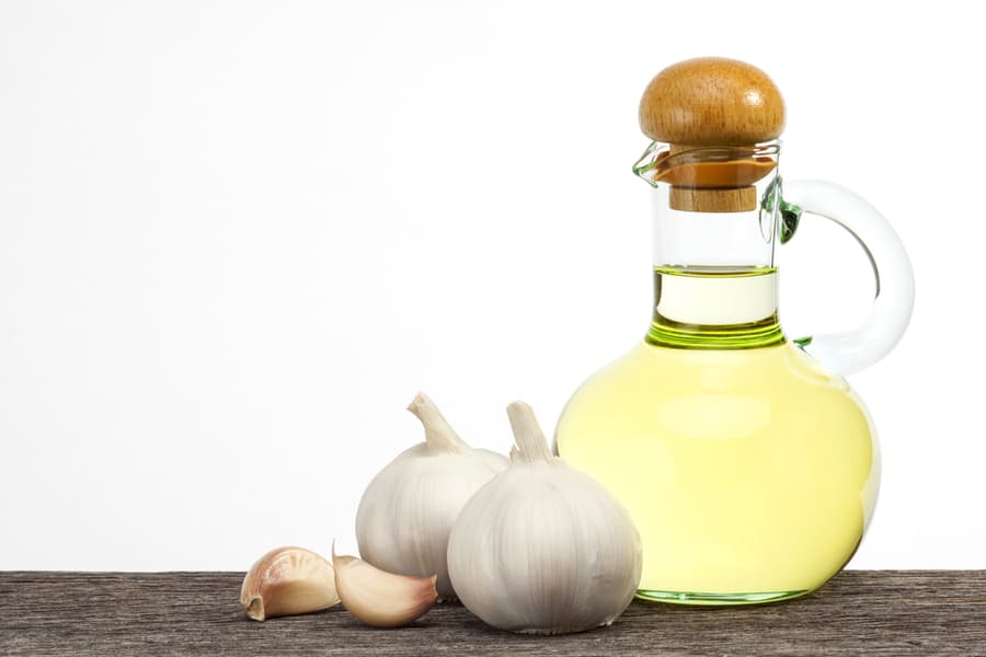Garlic Oil In Bottle Glass On The Old Plank Wood